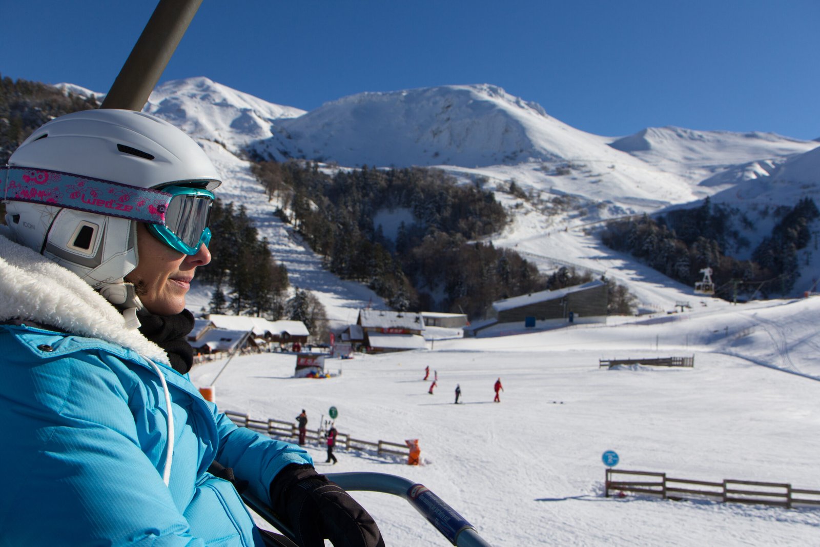 Skieuse sur un télésiège face aux pentes enneigées du Mont-Dore, dans le massif du Sancy