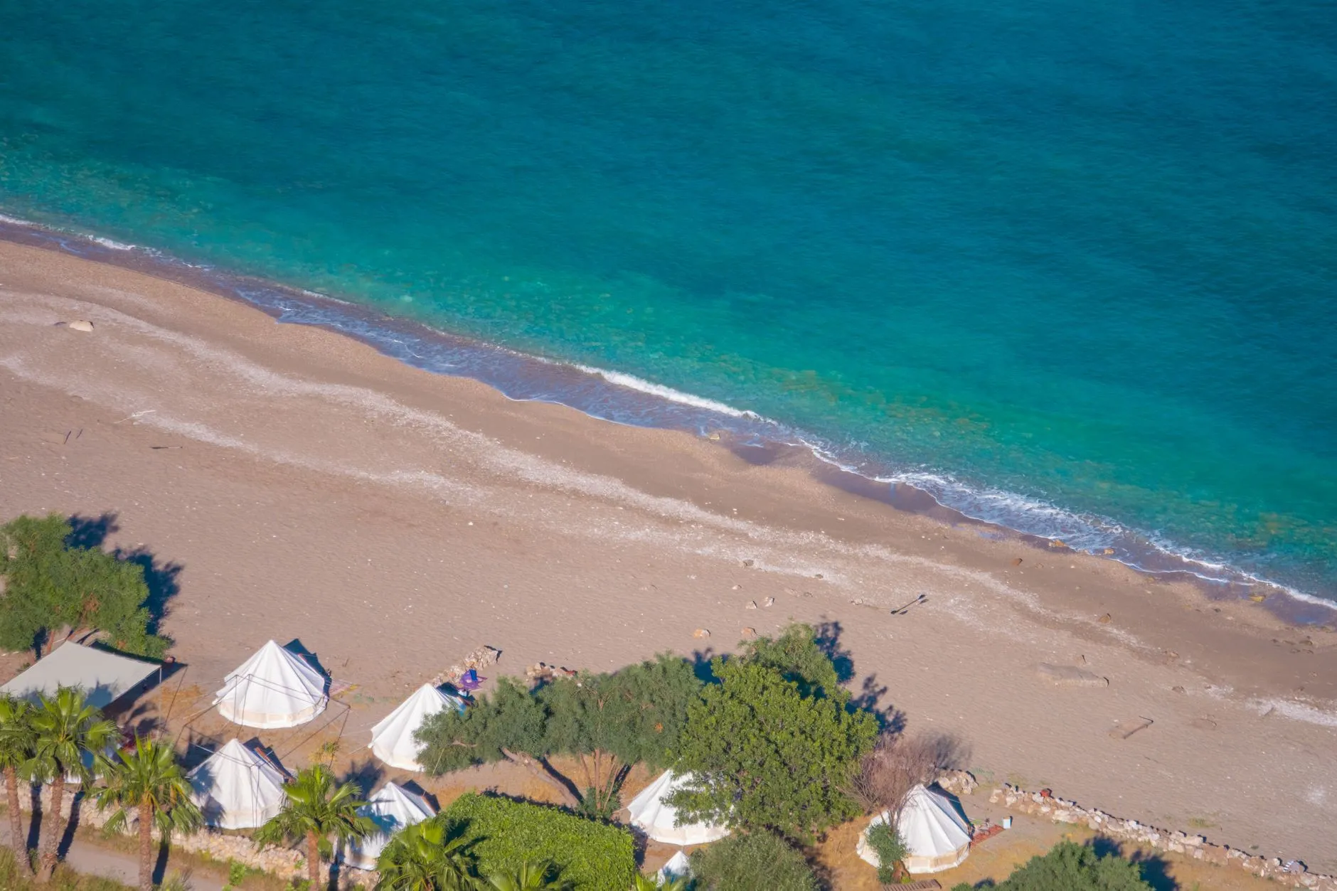 Vue aérienne de tentes installées en bord de mer face à une eau turquoise
