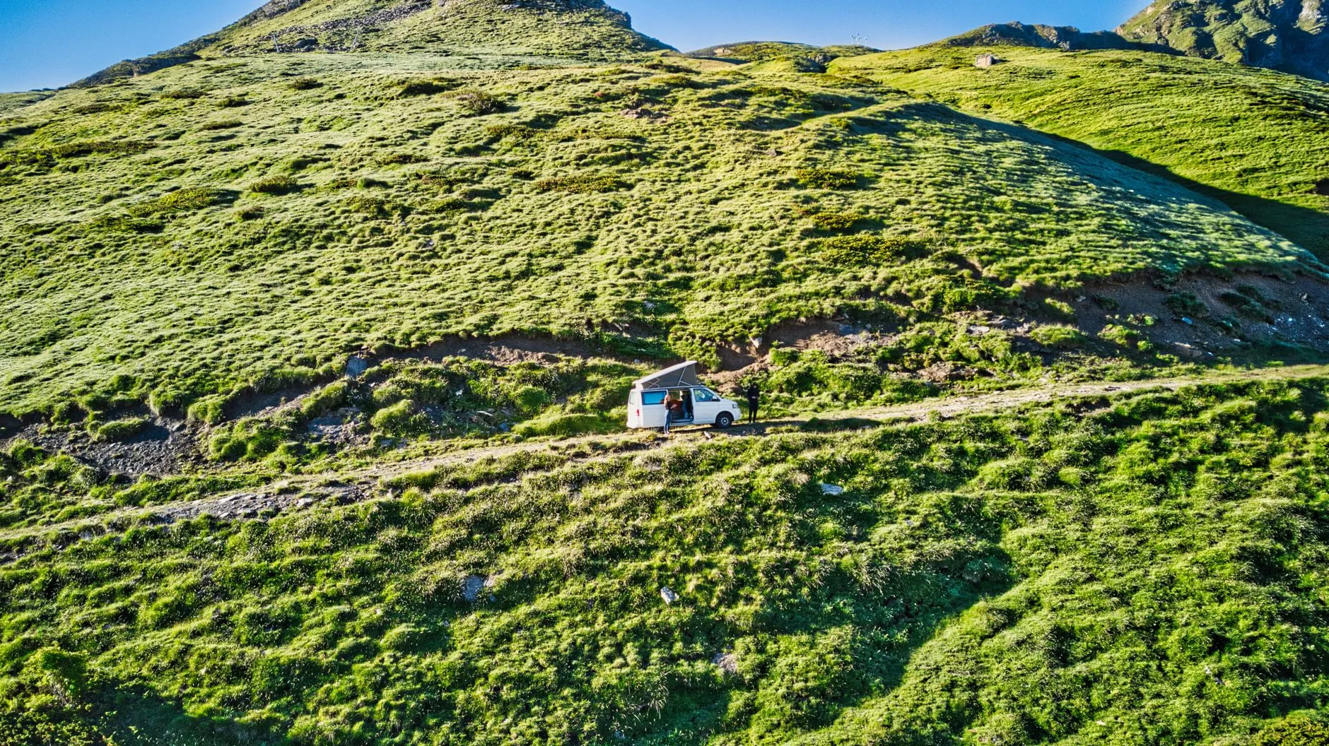 Van aménagé stationné le long d'une route de montagne au coucher du soleil