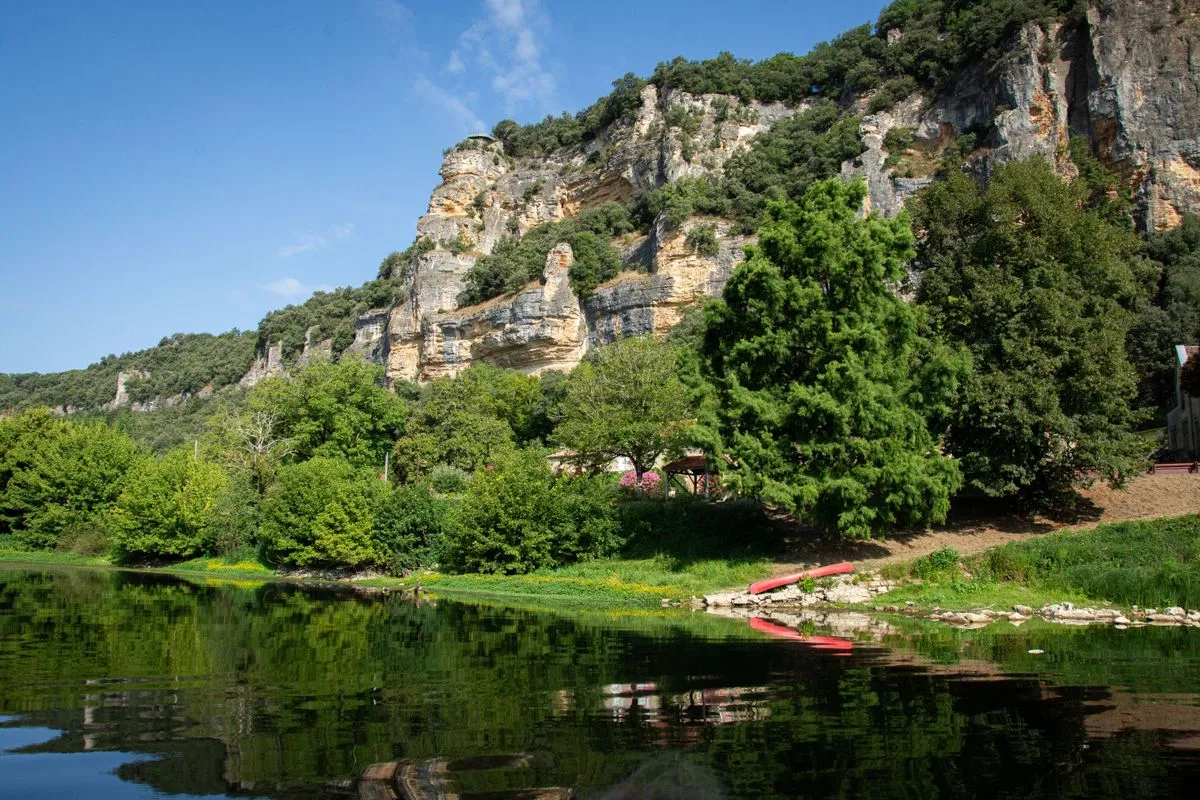 La vallée de la Dordogne, ses falaises calcaires et un canoë rouge sur la rivière