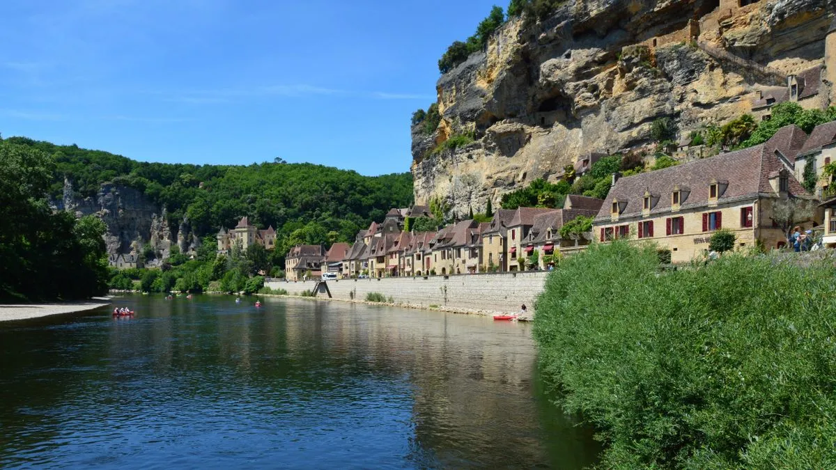 La Roque-Gageac, village accroché à la falaise au bord de la Dordogne, avec des canoës sur la rivière