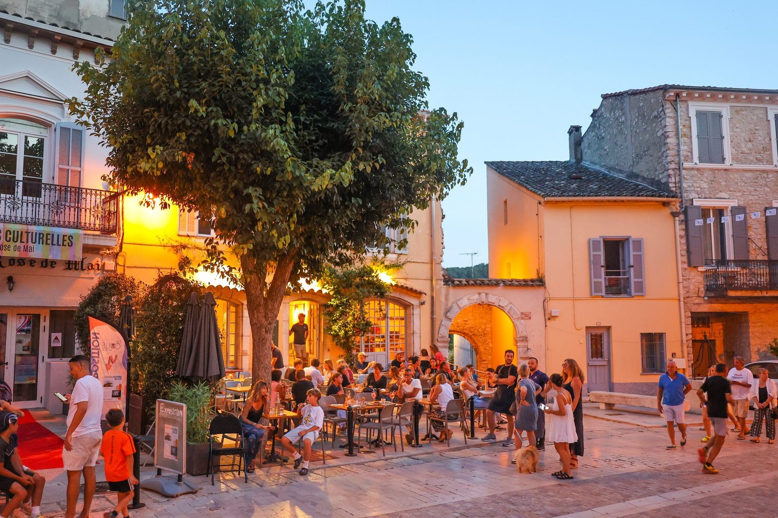 Terrasses animées sur la place du village de La Colle-sur-Loup à la tombée du jour