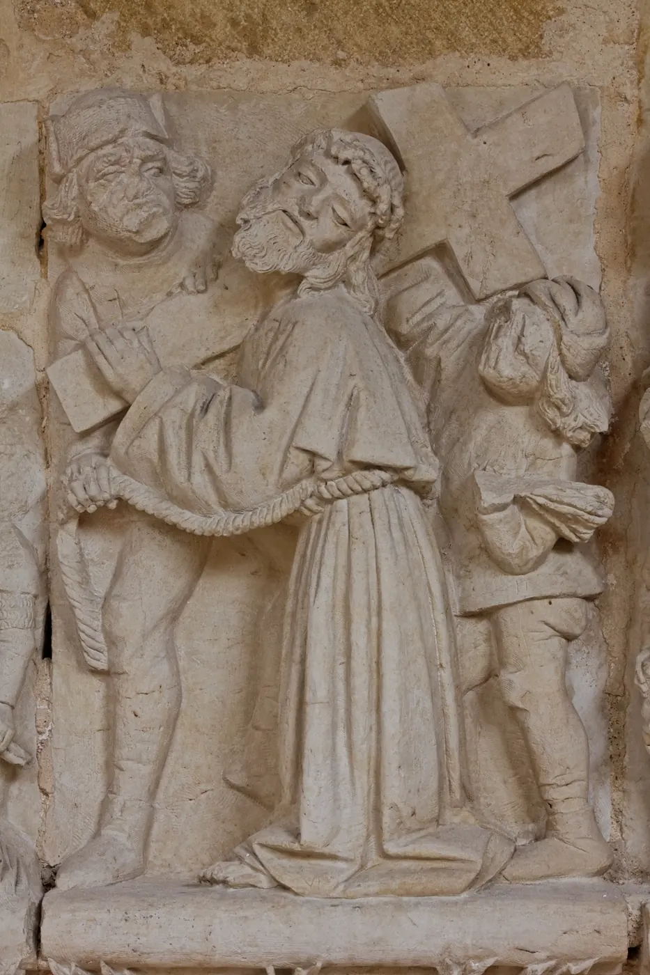 Bas-relief sculpté du cloître de Cadouin représentant un personnage portant une croix