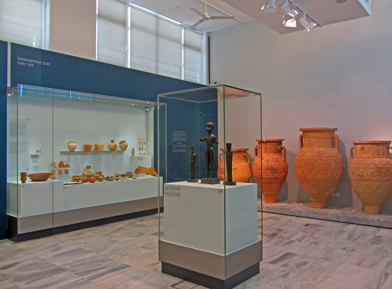 Une salle du musée archéologique d'Héraklion avec vitrines de céramiques et grandes jarres minoennes