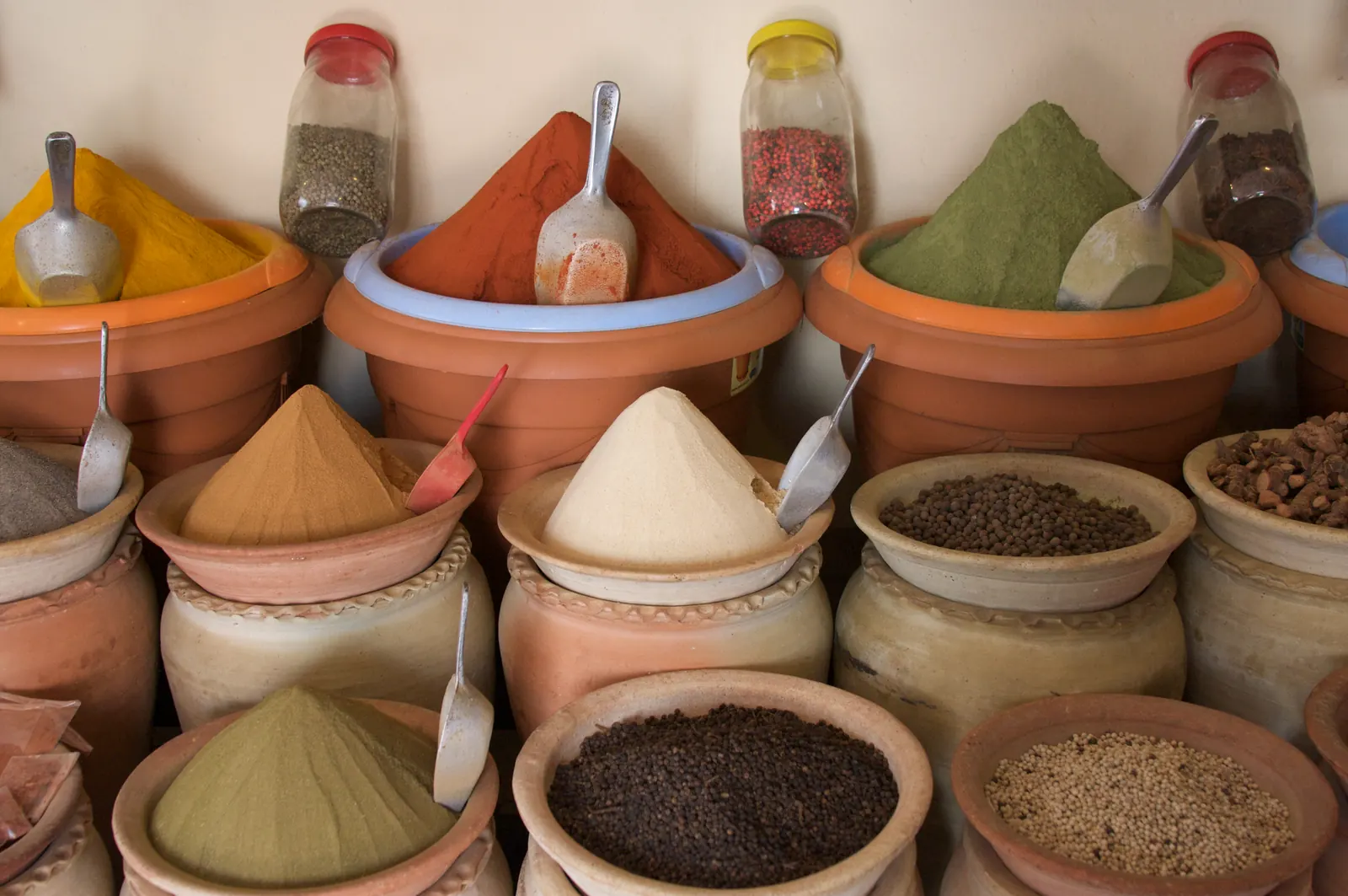 Pots de terre cuite remplis d'épices en poudre colorées sur un étal du souk de Houmt Souk, à Djerba