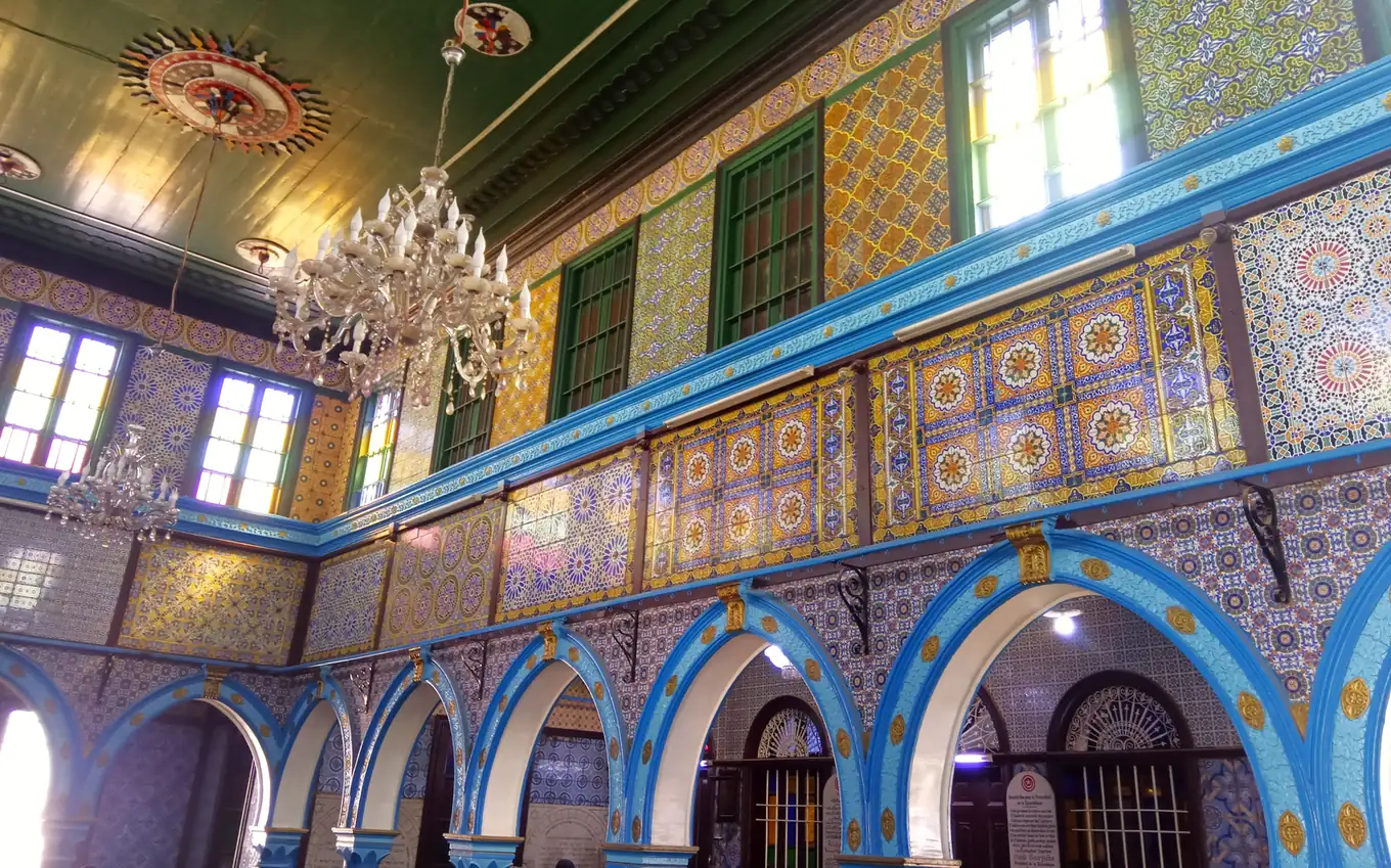 Intérieur de la synagogue de la Ghriba à Djerba, avec ses arcades bleues, ses faïences colorées et ses lustres
