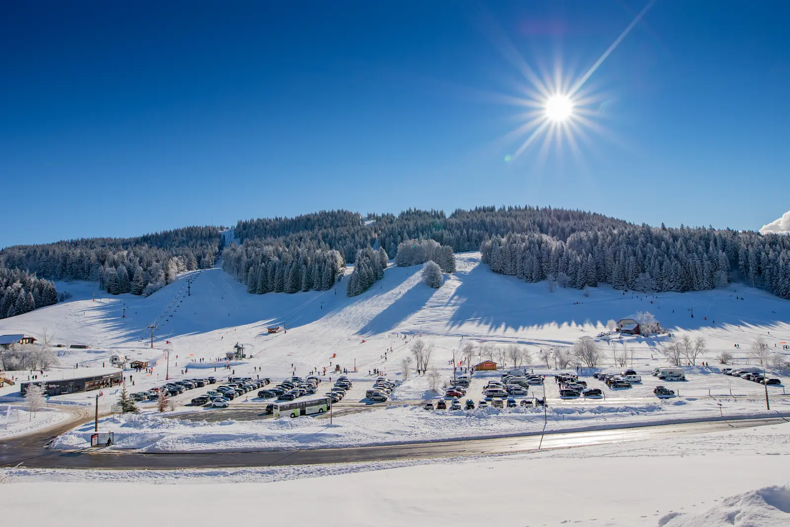 Un front de neige de la station et son parking, sous le soleil d'hiver