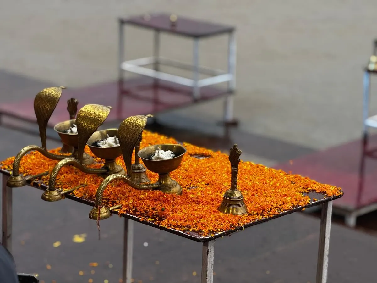 Lampes à huile en laiton en forme de cobra et clochette posées sur un lit de fleurs d'œillet d'Inde orange, avant l'aarti à Rishikesh