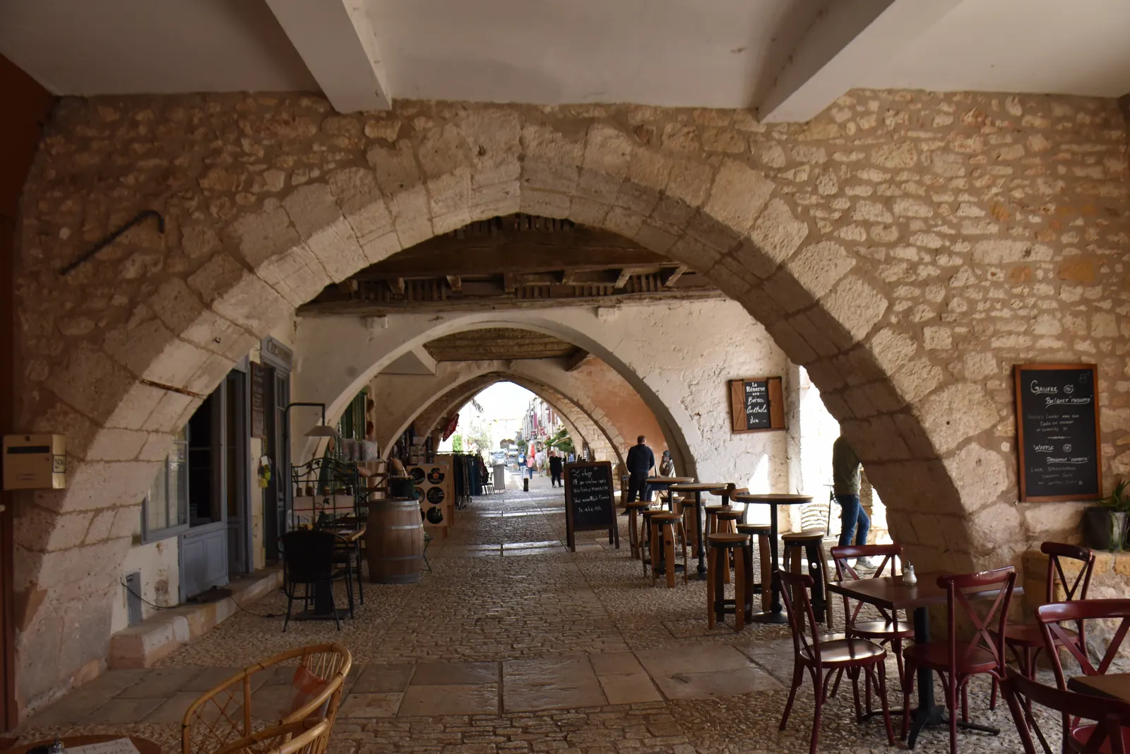 Galerie couverte sous les arcades de pierre de la place des Cornières à Monpazier