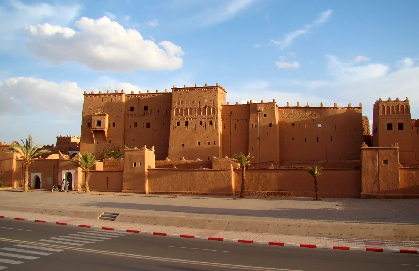 La façade ocre crénelée de la kasbah de Taourirt au bord de l'avenue Mohammed-V à Ouarzazate