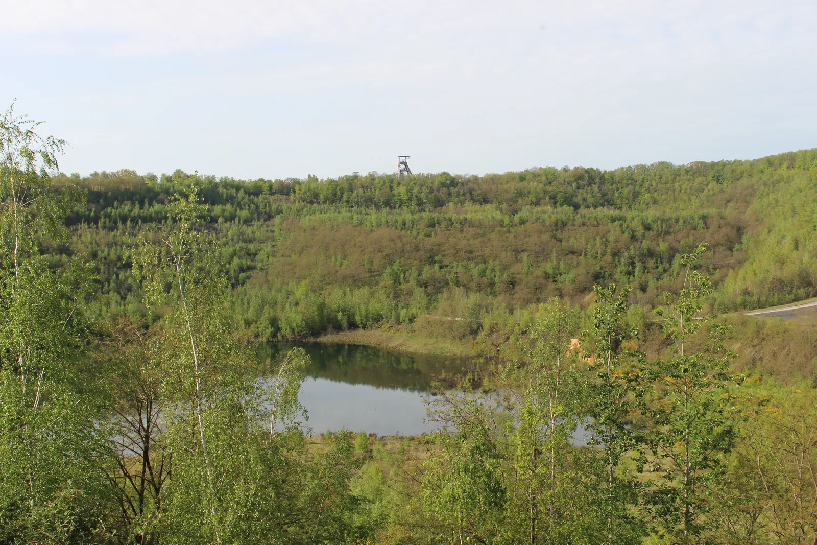 Le lac de la carrière Simon vu depuis le haut des anciens fronts de taille, un chevalement à l'horizon