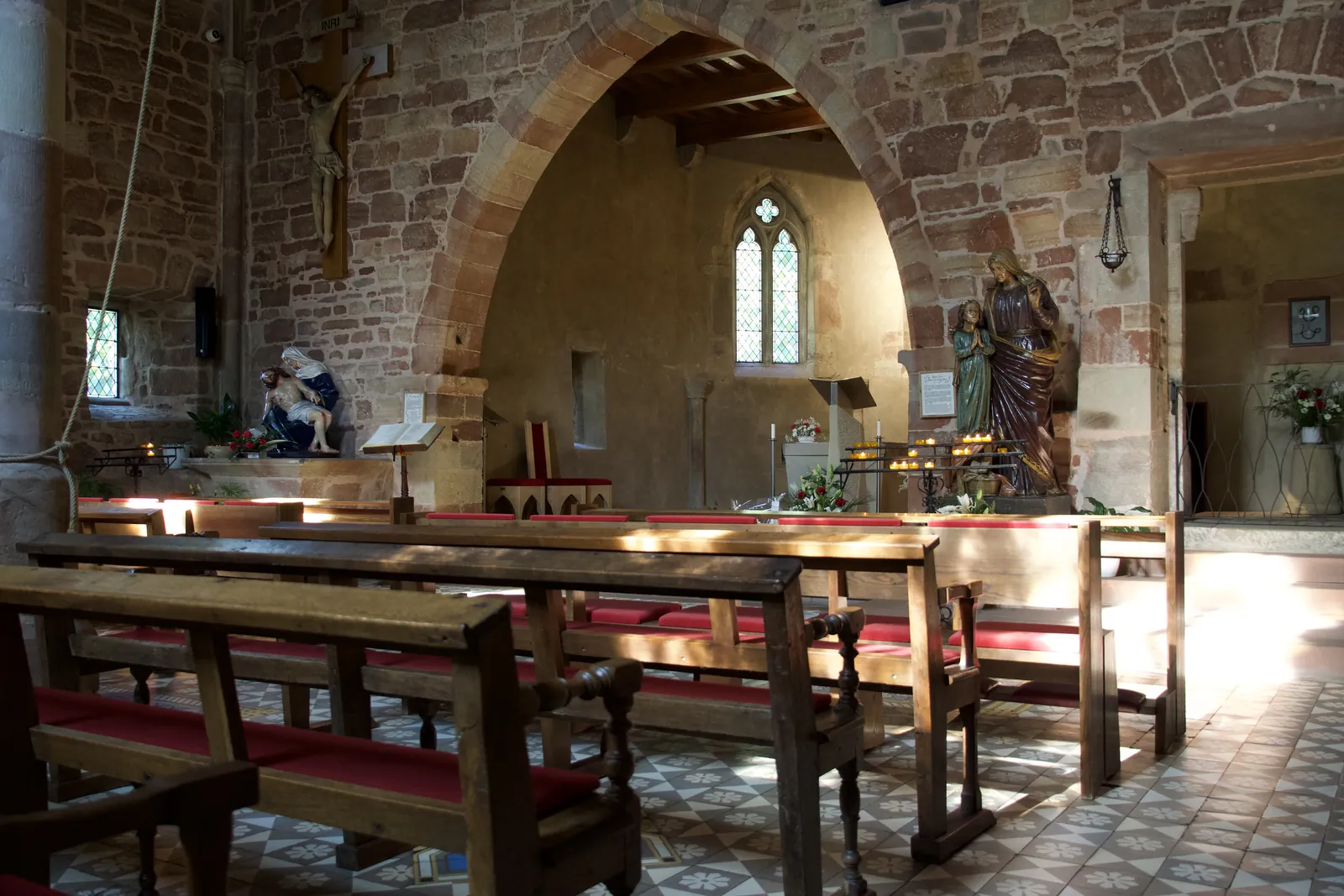 Intérieur de la chapelle Sainte-Croix de Forbach : bancs, arc en grès et chœur