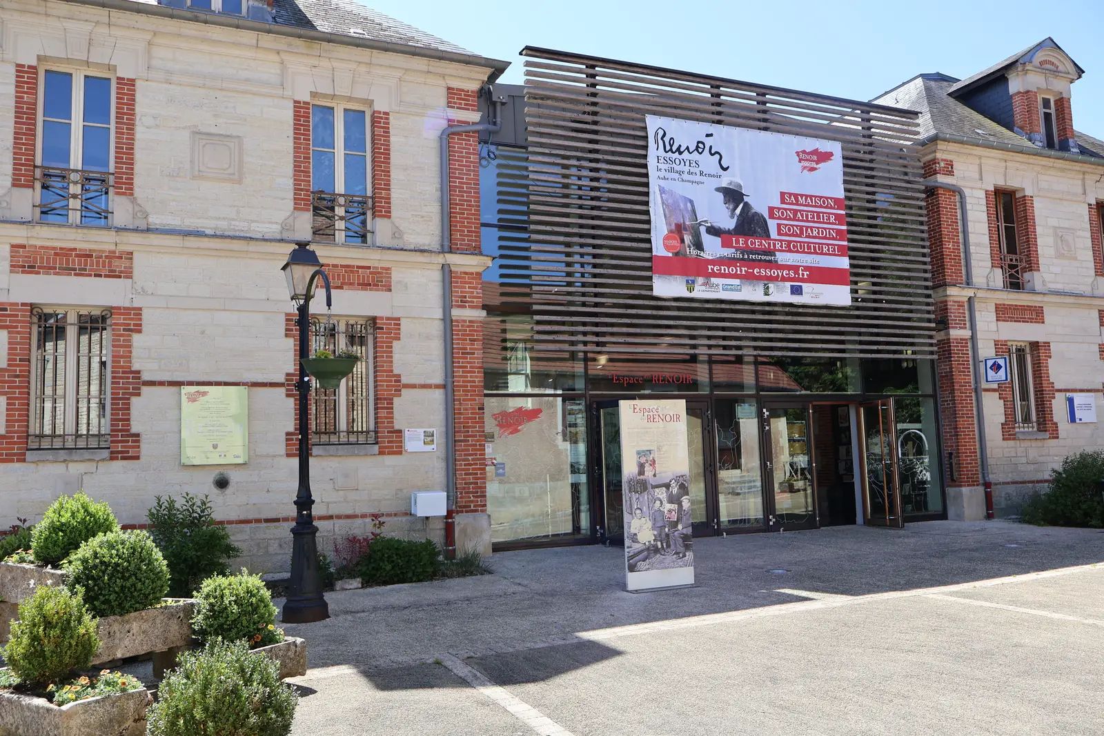 La façade du Centre culturel Renoir à Essoyes, entrée vitrée entre deux pavillons de pierre et de brique